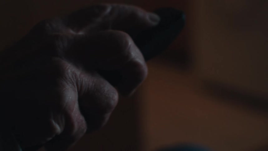 Elderly man sitting using television remote control