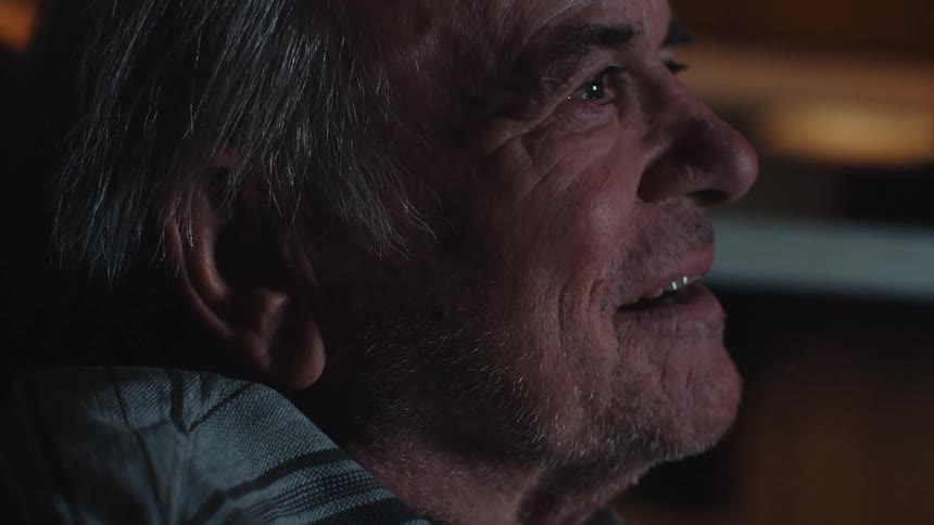The light from the television flickers on the mans face