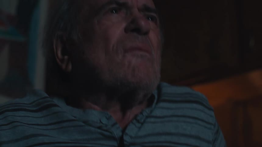 A man leans forward while watching television