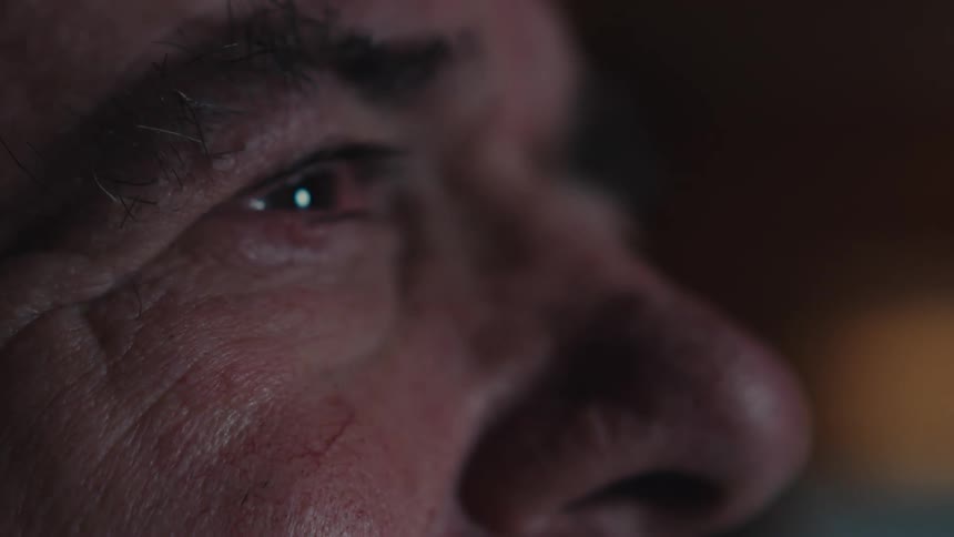 Close up of the eyes of an elderly man watching tv