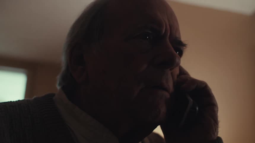 Man looks concerned while talking on the phone in his house