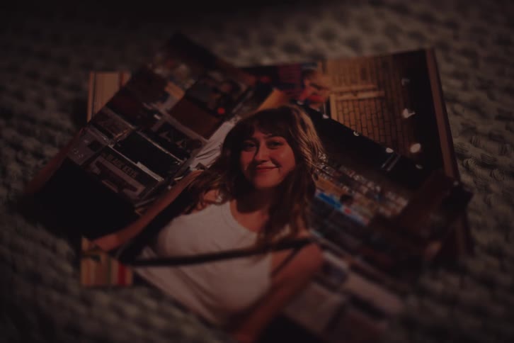 A close up view of a stack of photographs with one image of a young woman smiling clearly visible
