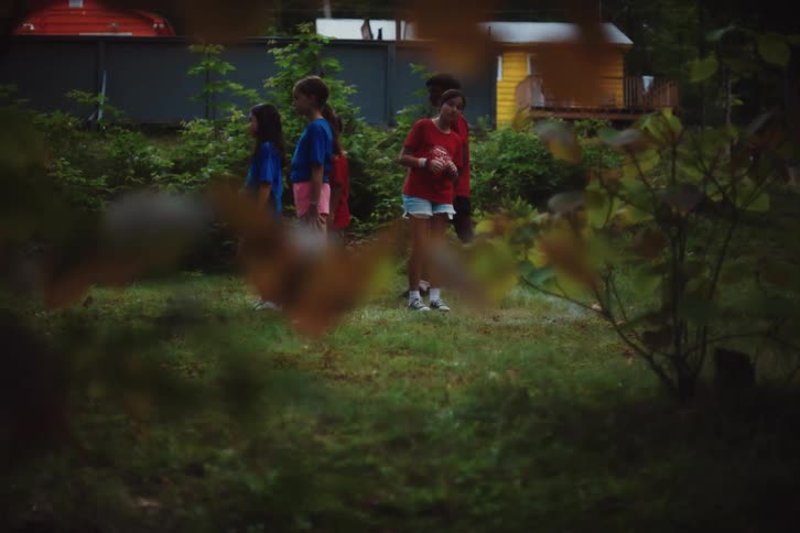 Boy runs while two teams play a game at camp