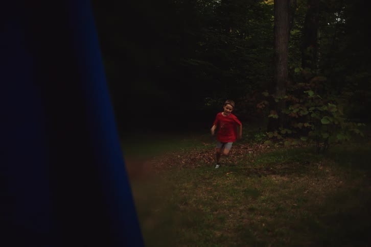A child hides behind a tree grabs a blue flag and runs away in a game