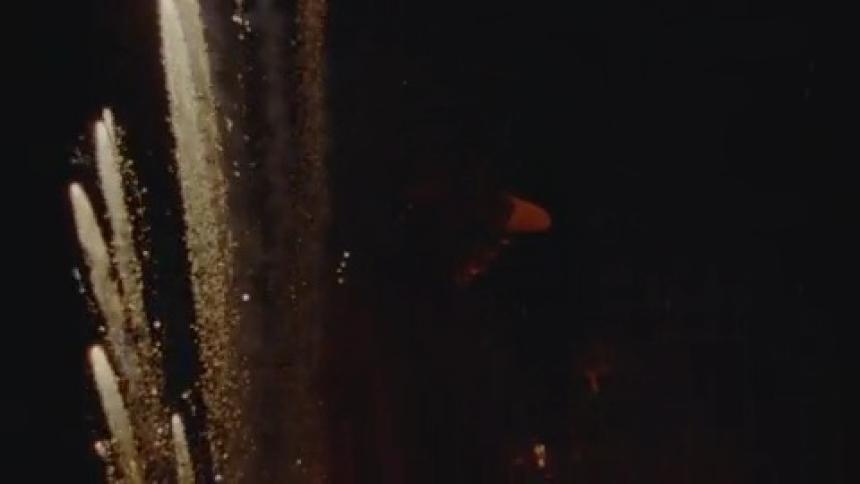 Man facing to the right with fireworks shooting off behind him