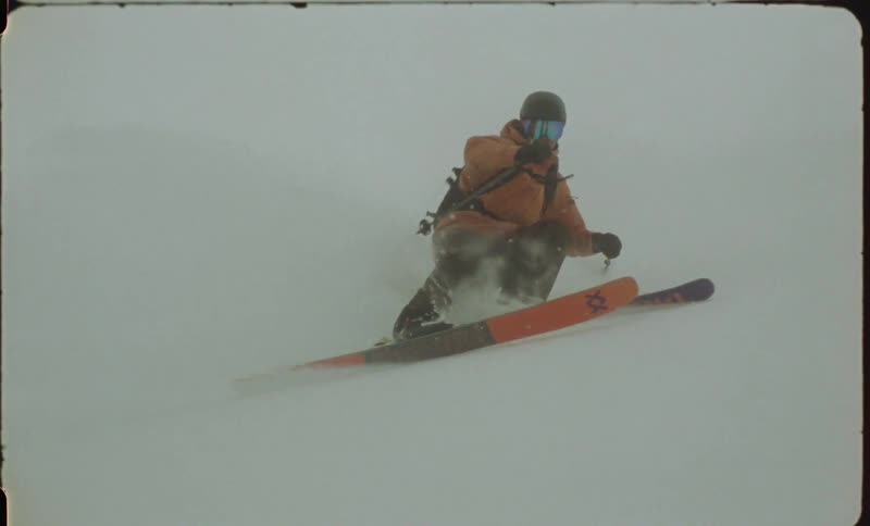 A person bundled up for the cold skis down a snow covered mountain slope