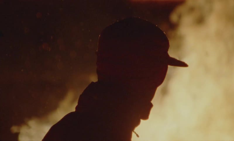 Portrait of a person in a cap next to a burst of fire at night