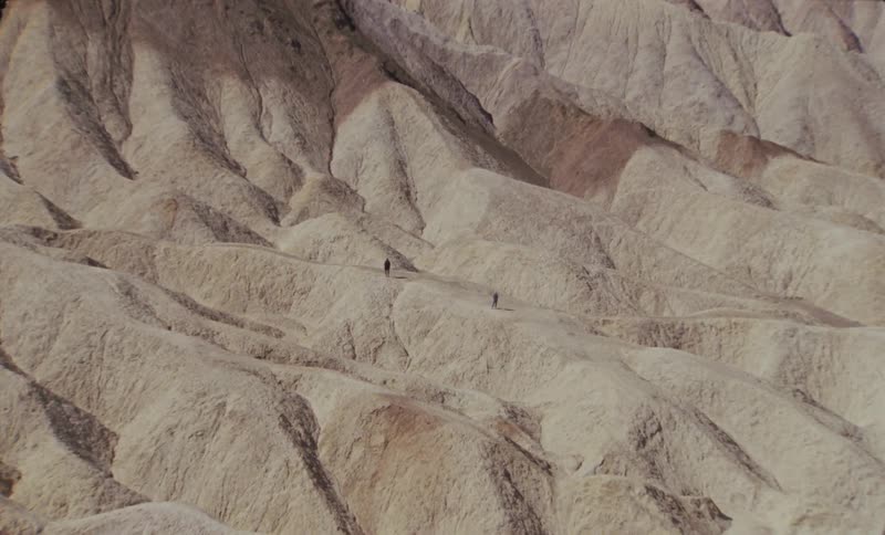 Two people standing still on a rocky mountain