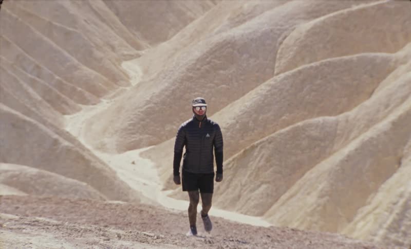 A lone hiker walking through undulating desert hills
