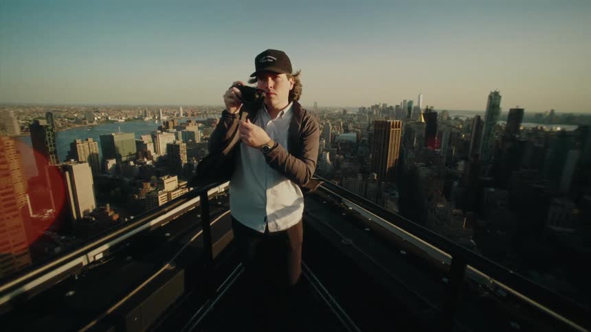 Photographer using his professional camera on the terrace of a building with a panoramic view of a metropolis