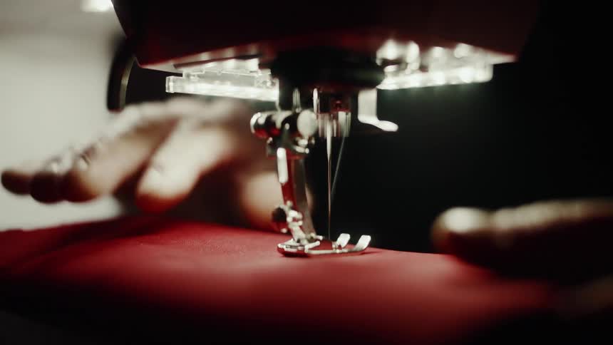 Hands working with red fabric on a sewing machine