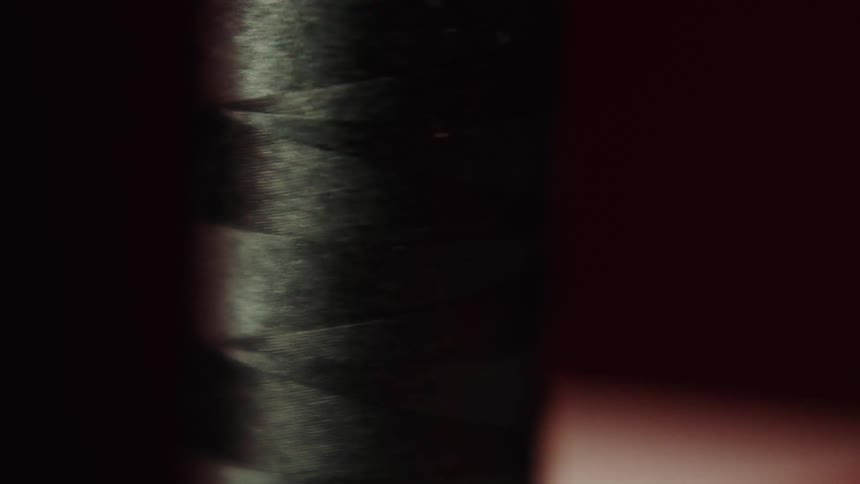 Black thread is pulled from the spindle