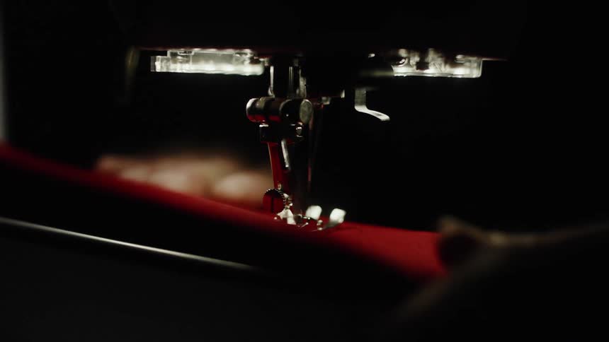 Hand working on a sewing machine with red fabric