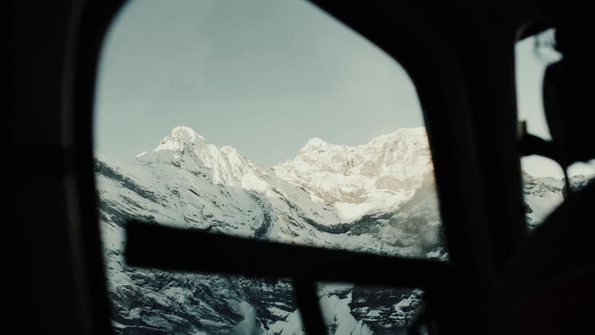 Snowcovered mountains seen through the window of a helicopter