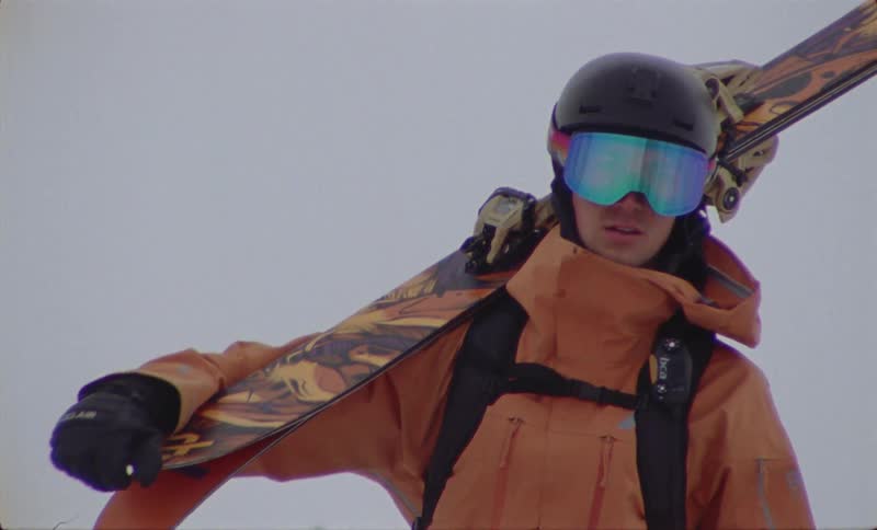 Person with helmet walking with ski equipment