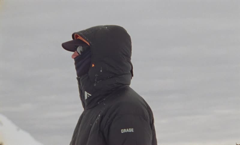 Man in cap glasses and winter jacket in a snowy outdoor environment