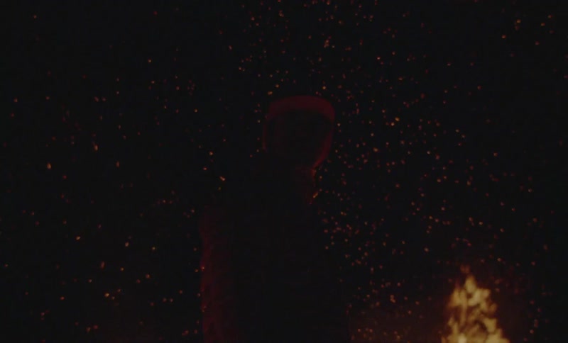 Silhouette of a person next to a fire at night