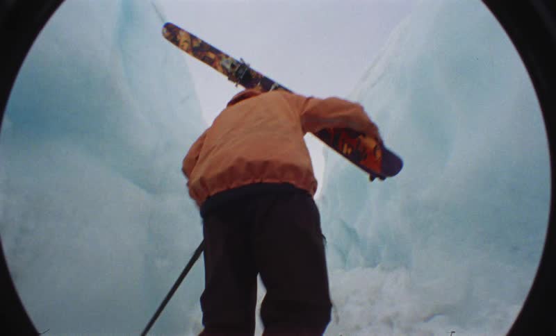 Person walking with ski equipment in the middle of a narrow glacier