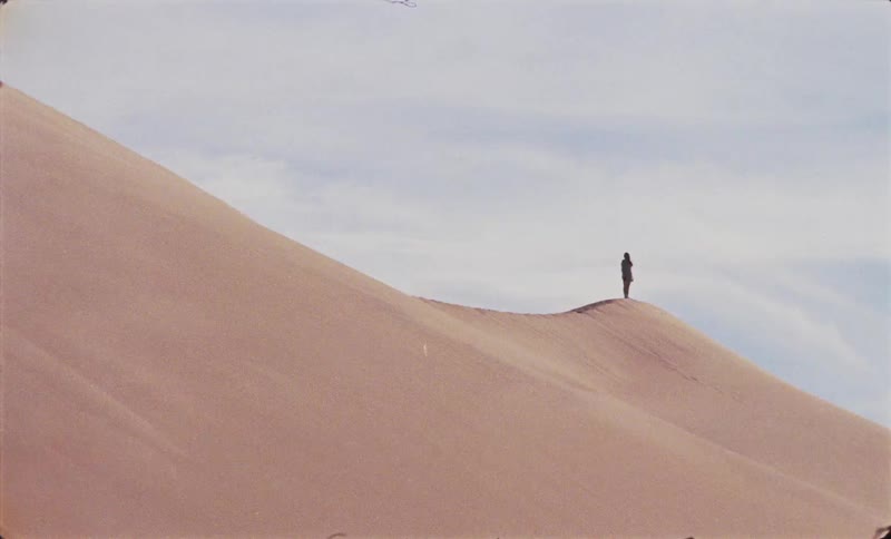 Lone individual stands on a hill in the desert on a cloudy day
