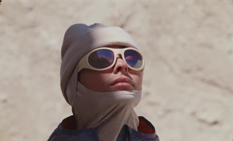 Portrait of a woman with closed eyes wearing glasses and a cap in an outdoor natural setting