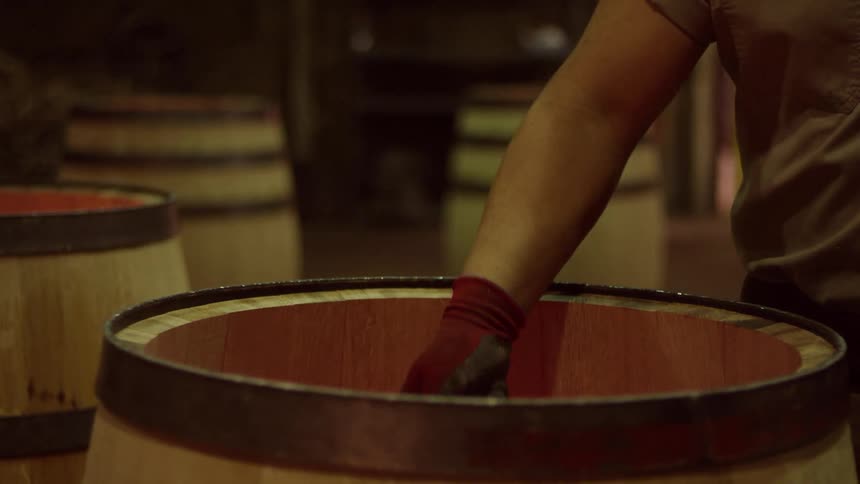 A worker placing wood into a barrel as sparks come out of it