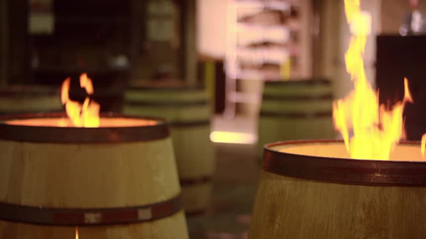 Fire burining inside two wine barrels outdoors at night