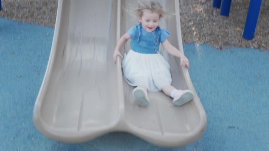 Little girl going down a slide at a playground