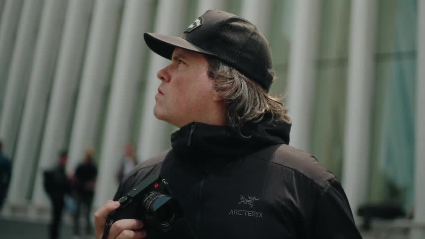 Man in an outdoor environment holding a professional camera