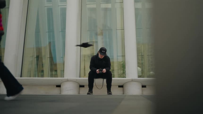 A clip of a person sitting outdoor with a camera