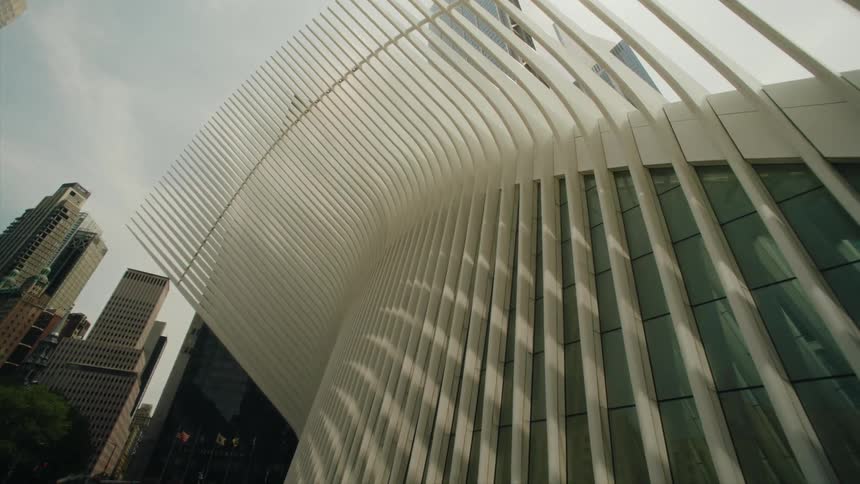 The facade of a large building with architecture with some pillars sticking out and glass windows
