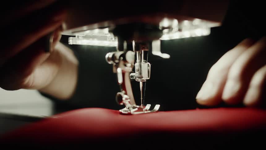 A sewing machine in action stitching fabric under precise light