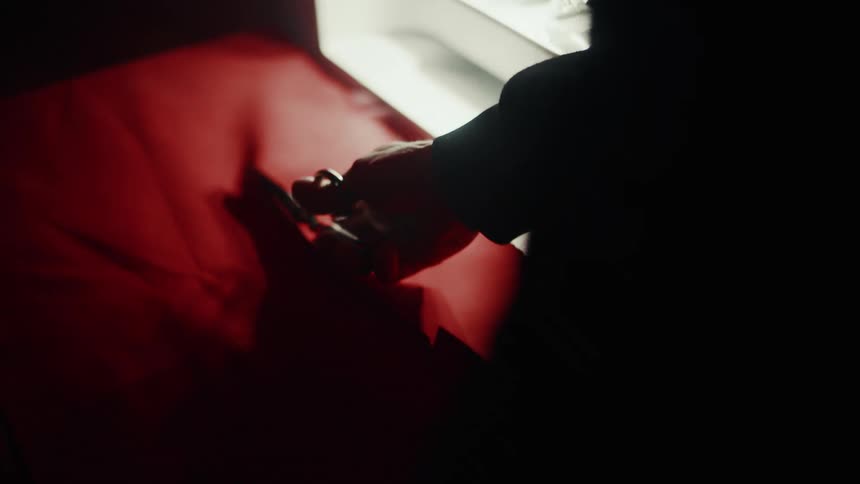 Hand with scissors cutting a red fabric