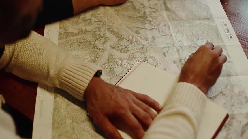 Hands tracing routes on a detailed map for planning