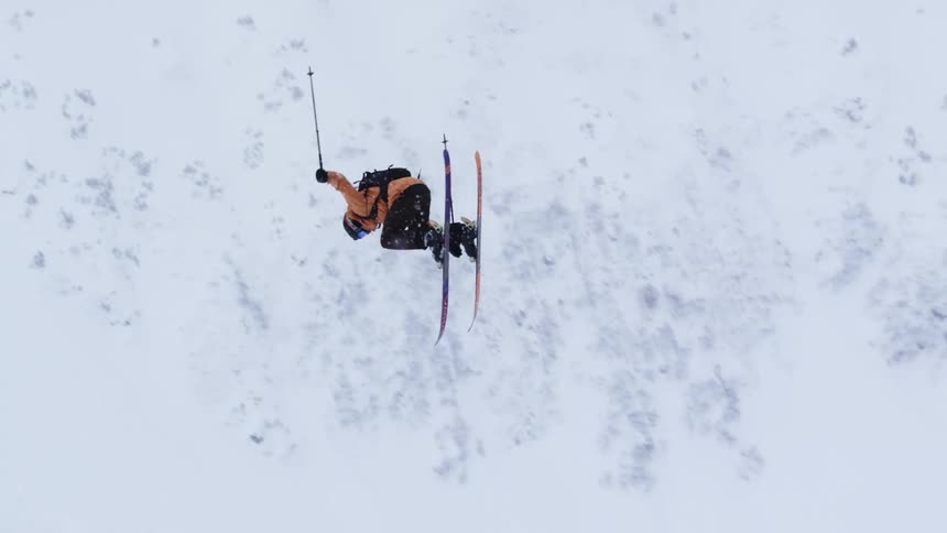 A man does a high jump and landing while skiing