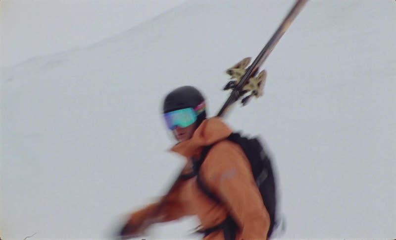 A person in winter clothes and with ski equipment is walking on a white snow