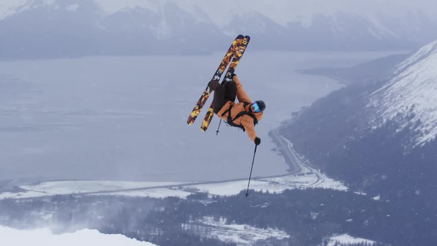 Skier performing an aerial trick in a snowcovered mountain landscape