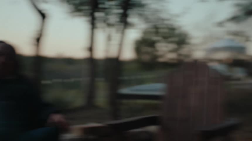 Friends sit outdoors in a rural backyard during an enjoyable conversation