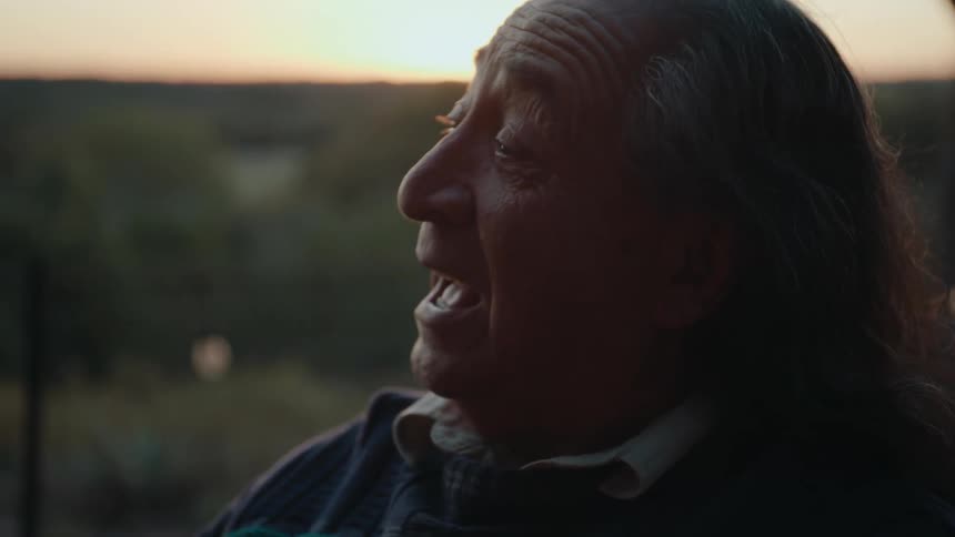 A man is smiling and talking outside