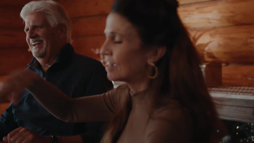 A group of people play cards over drinks at a table inside a home