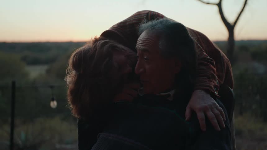A couple embrace while outdoors as the sun sets