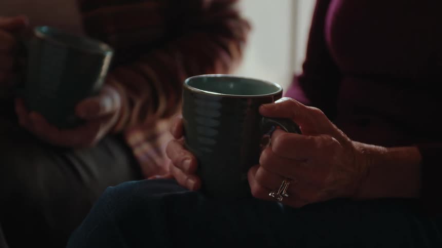 Two people are holding ceramic mugs
