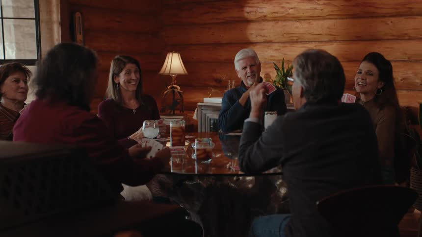 Group of people sitting at a table playing cards