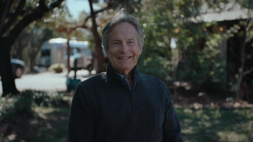 Elderly man in the garden in the backyard of a house smiling