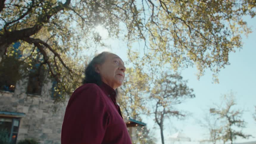 Elderly man walking in a yard with trees