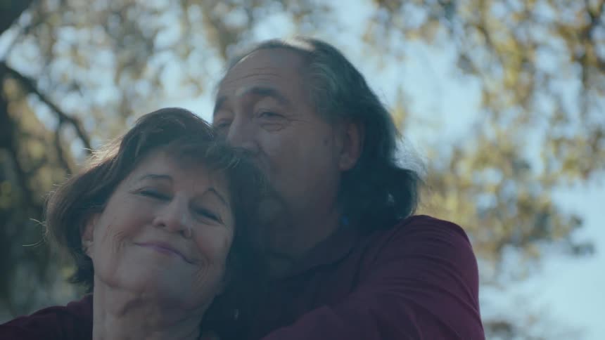 Elderly couple lovingly embracing beneath a tree