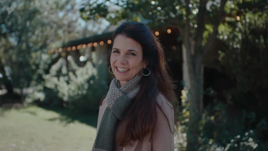 Woman in a backyard with trees smiling