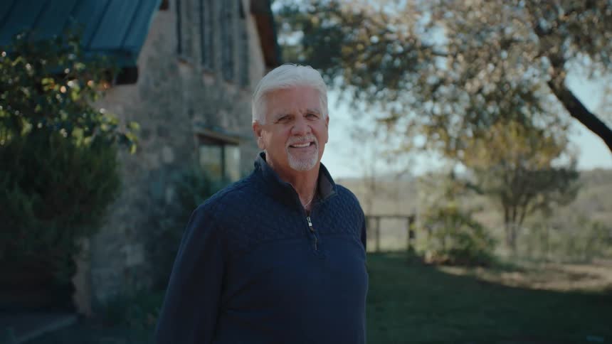 A man smiles in his yard