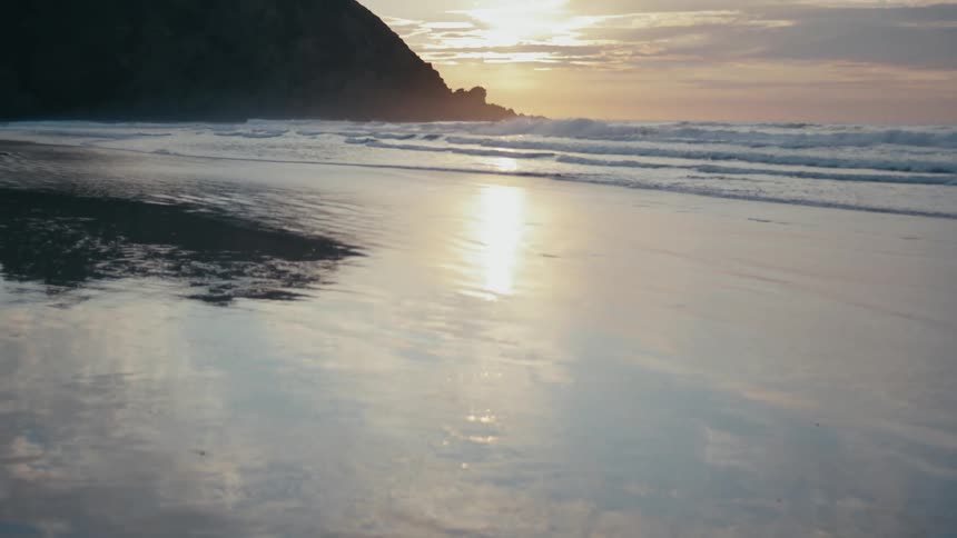 The rising sun reflects on the beach water