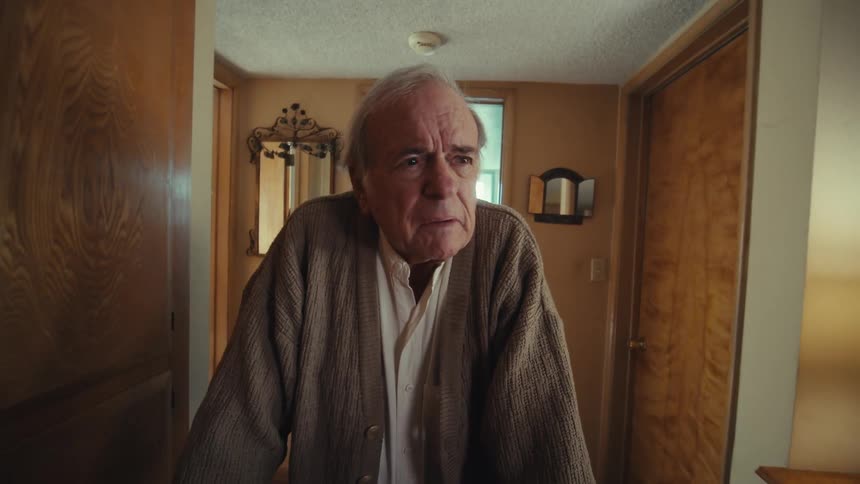 Elderly man leaving the bathroom and walking down the hallway of the house