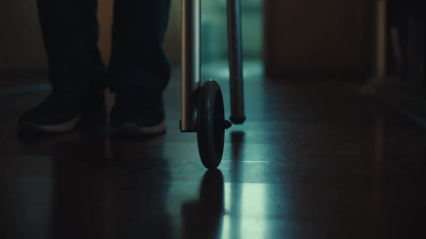A person is using a walker on a reflective floor